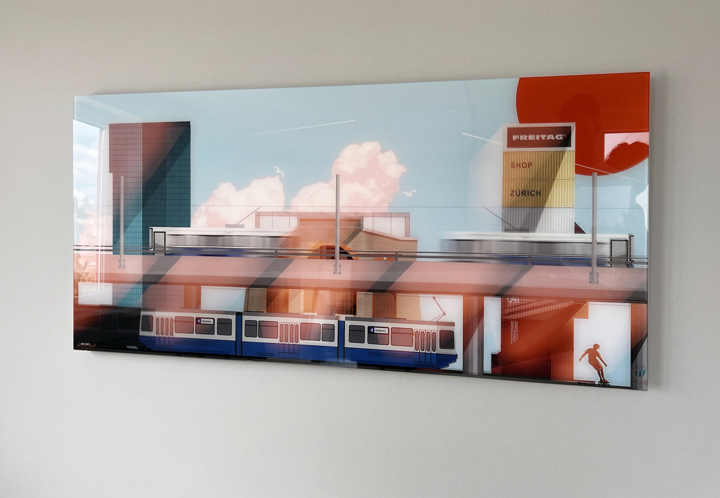 A rectangular wall art print on plexiglas showing an abstract city street scene with a train, buildings, clouds, and bold orange-red geometric shapes, mounted on a light gray wall.